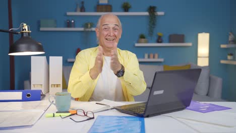 Home-office-worker-old-man-looking-at-camera-clapping-and-getting-excited.
